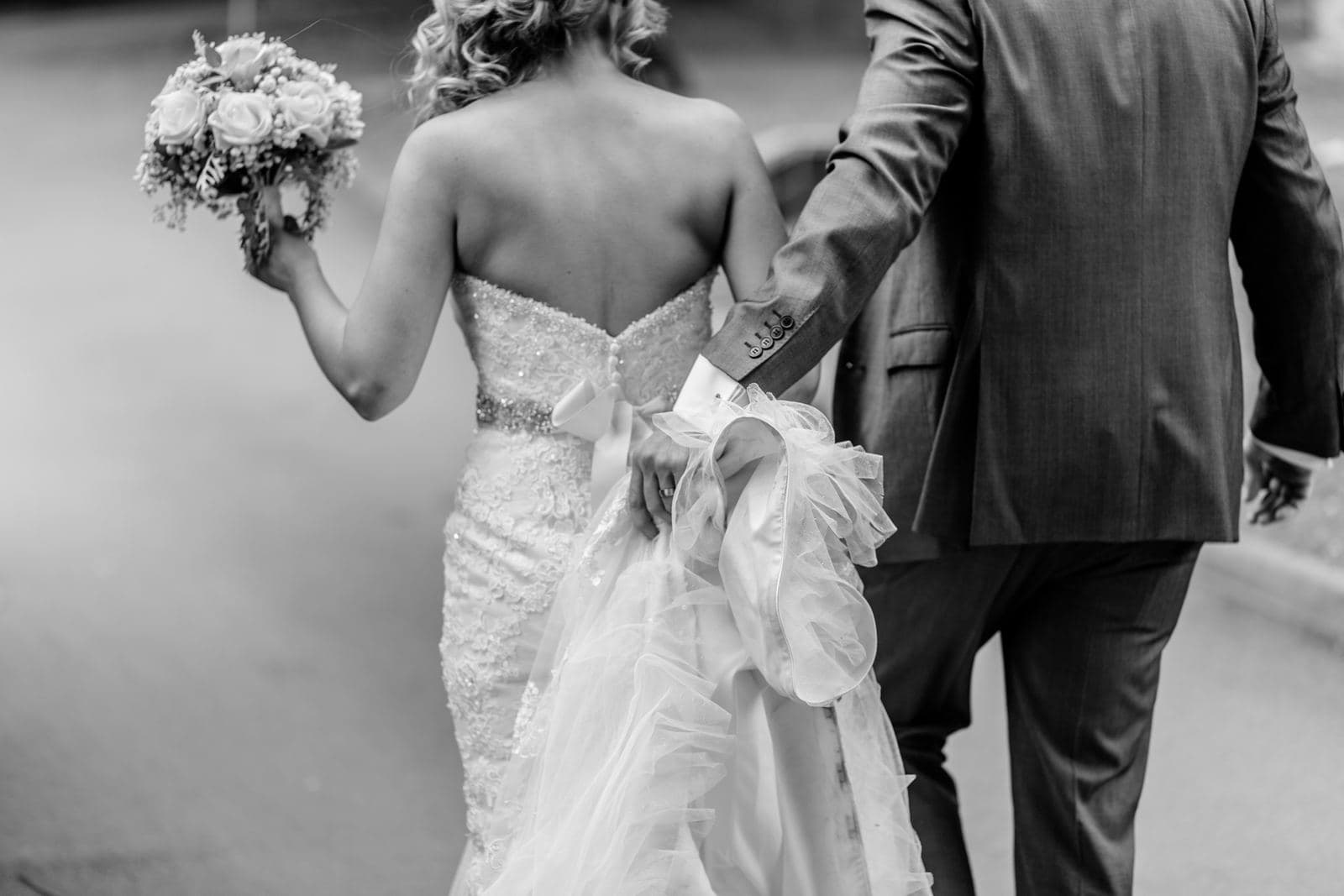 Bruidspaar loopt hand in hand, bruid met boeket